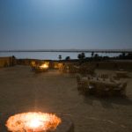 Traditional stone-built hotel in Siwa Oasis surrounded by palm trees and desert landscape.