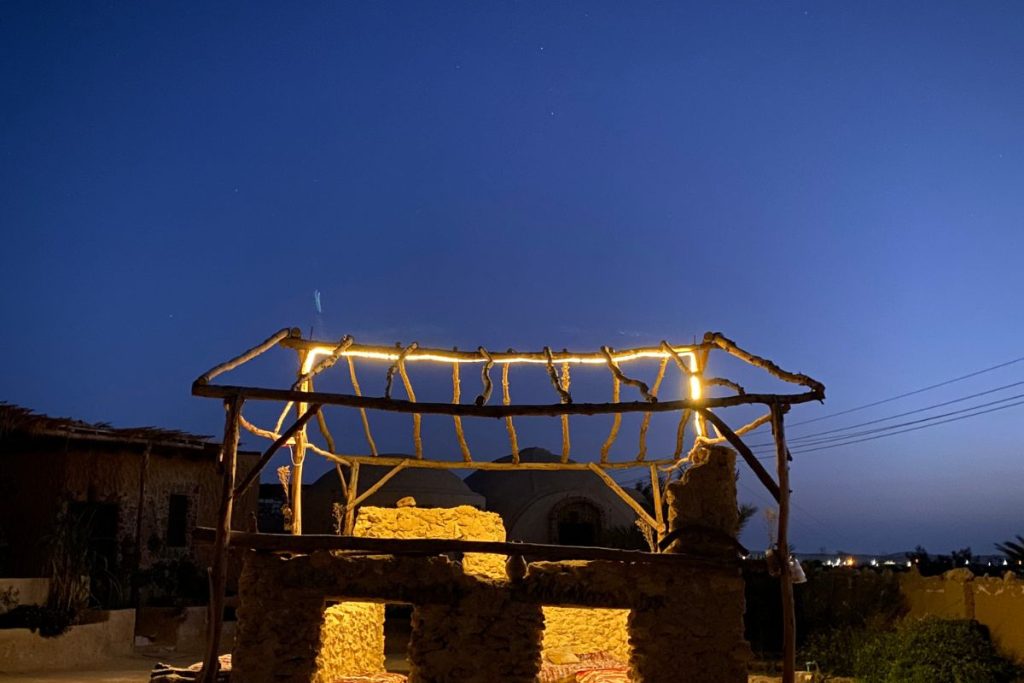 Rustic pergola illuminated at night with a clear sky in the background