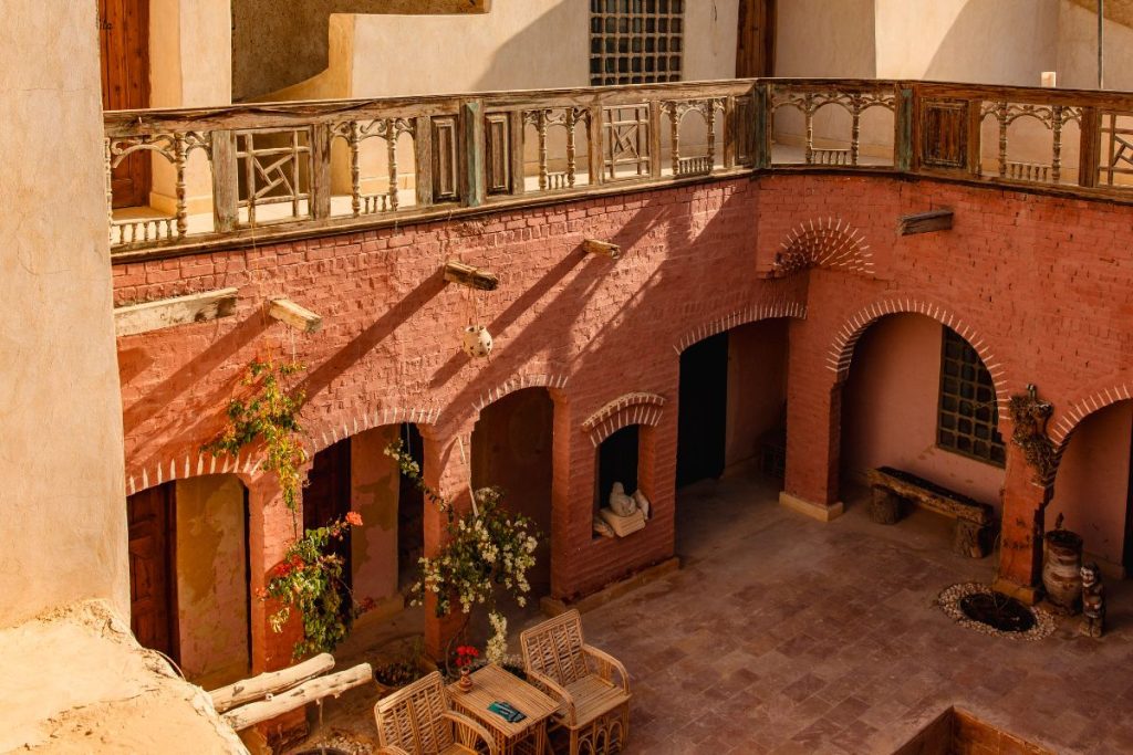 Courtyard of a traditional desert building with red brick walls and wooden balconies