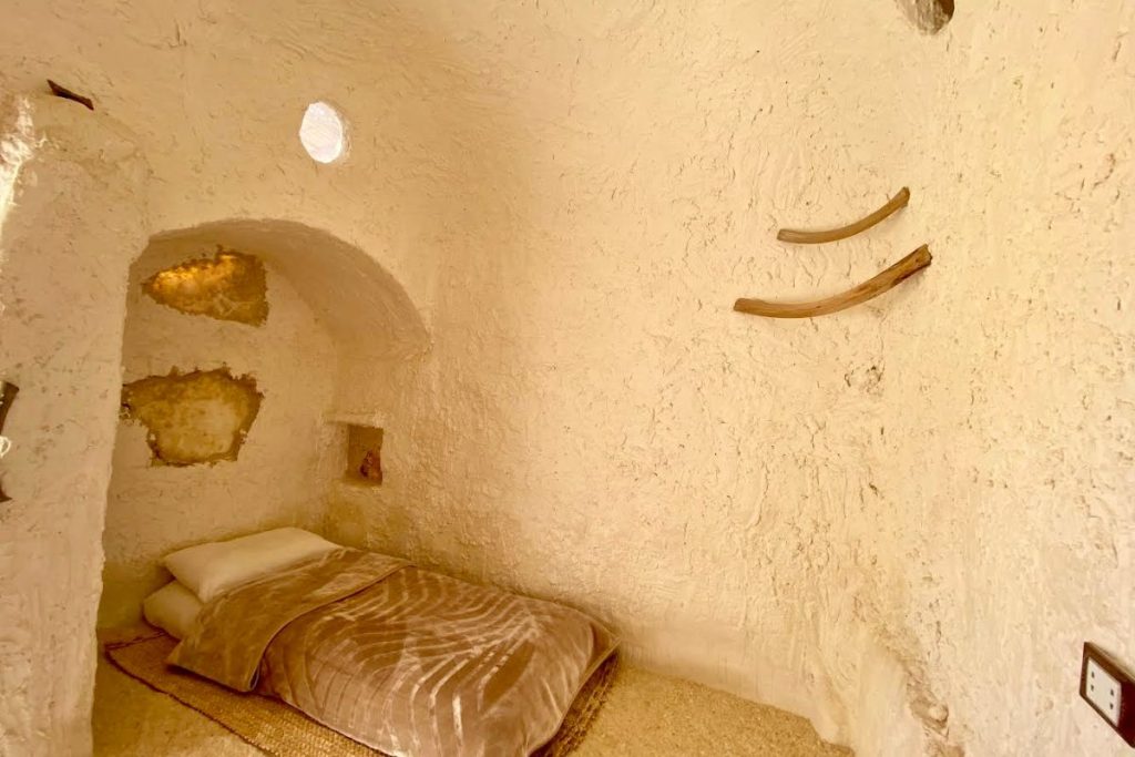 Small cozy bed in a traditional dome-shaped desert room with minimal decor