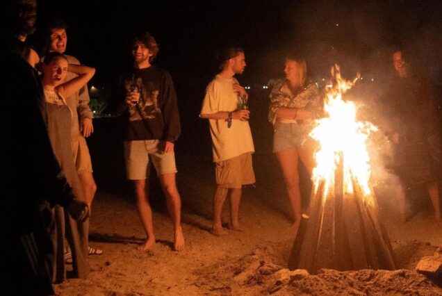 Group of friends enjoying a beach bonfire at night