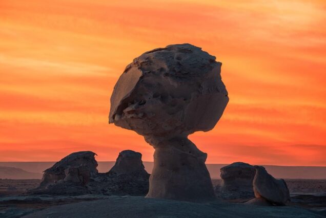 Mushroom-shaped rock formation in a desert at sunset