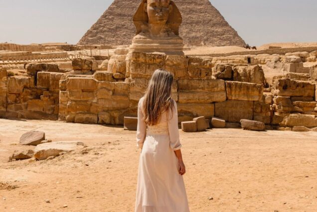 Romantic couple sitting near the Pyramids of Giza with camels in the foreground