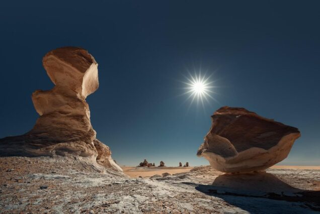 Sunlight shining over unusual rock formations in a barren desert