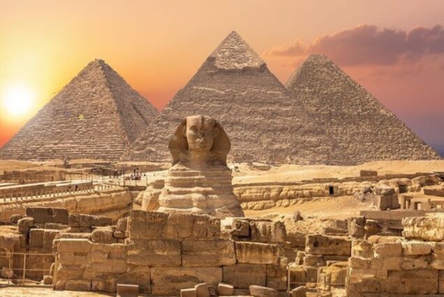 The Great Pyramids of Giza and the Sphinx at sunset with golden skies