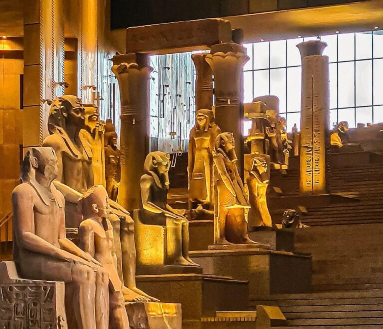 A museum hall with ancient Egyptian statues and columns, dimly lit with a warm golden glow