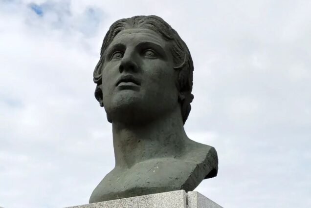 A statue of a heroic figure, made of bronze, gazing into the distance with a solemn expression