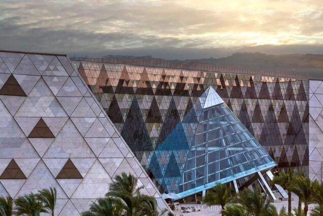 Modern museum with a unique triangular glass facade and patterned walls at sunset