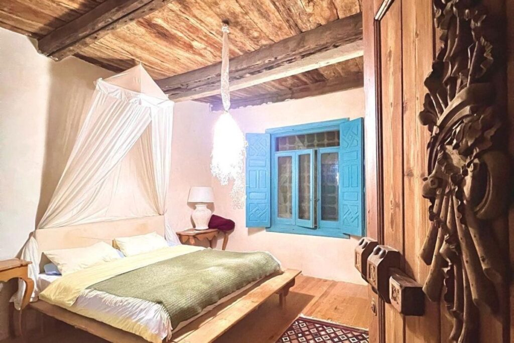 Rustic bedroom with a canopy bed and bright blue window shutters