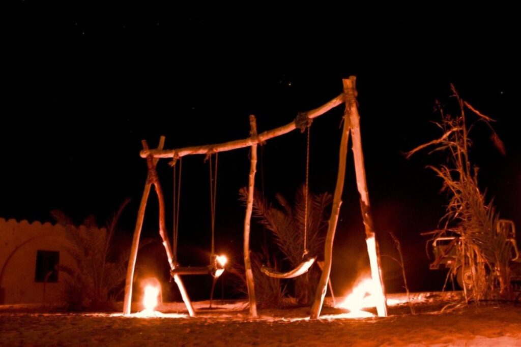 Rustic desert swing set glowing in firelight at night