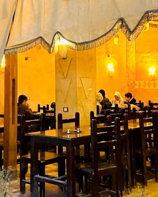 Inside Abdu Restaurant with guests sitting at wooden tables, enjoying their meals in a warmly lit, rustic environment with simple decor