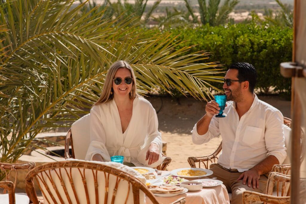 Couple enjoying a meal outdoors in a desert oasis setting