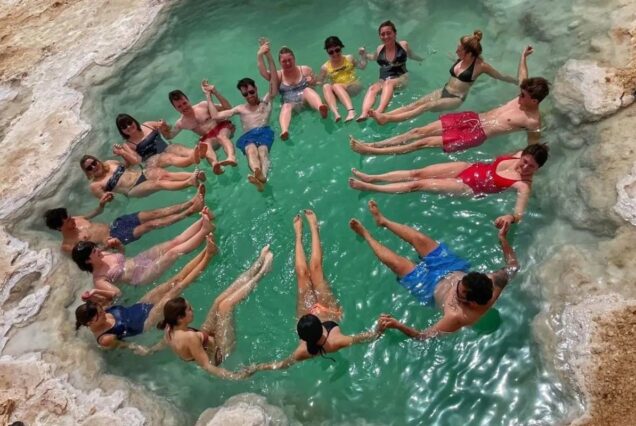 Group of people floating hand-in-hand in a circular saltwater pool