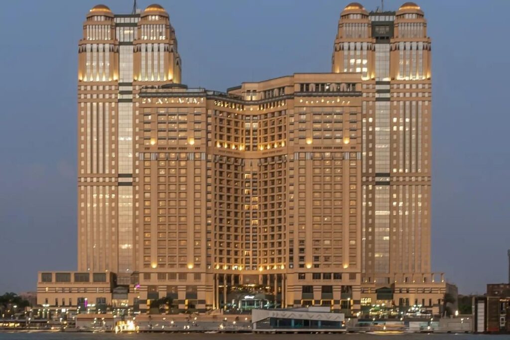 A large luxurious hotel with multiple towers, illuminated in gold light during the evening