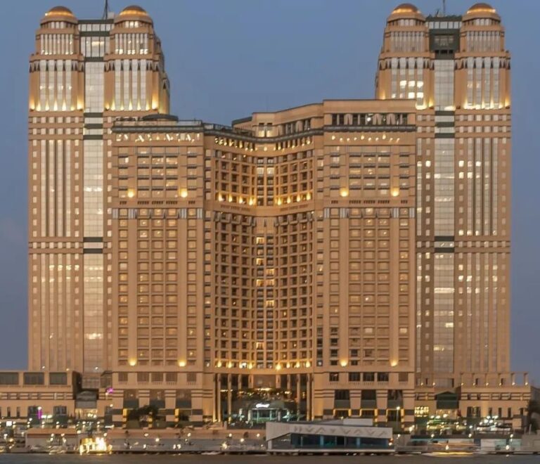 A large luxurious hotel with multiple towers, illuminated in gold light during the evening