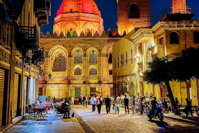 Historic street at night with illuminated architecture and people strolling