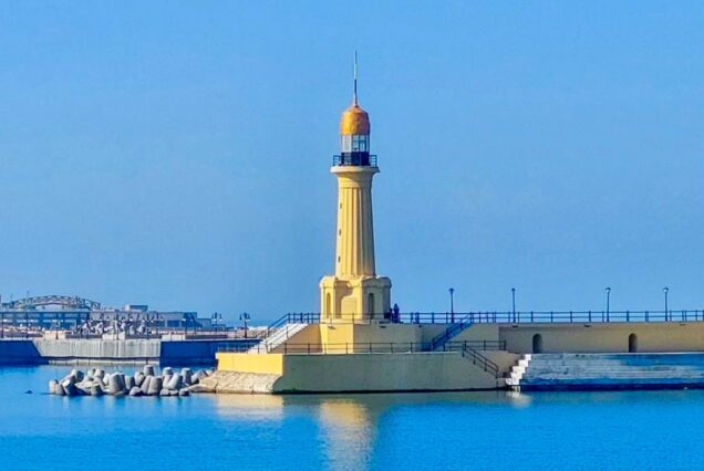 Yellow lighthouse on a pier surrounded by the blue sea