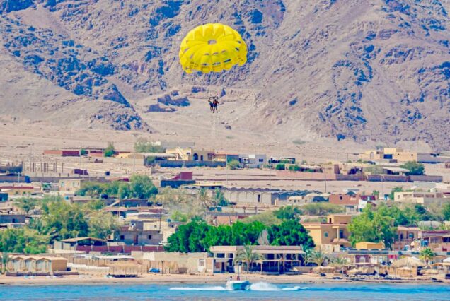 Parasailing over the coastal village with a backdrop of desert mountains in Egypt