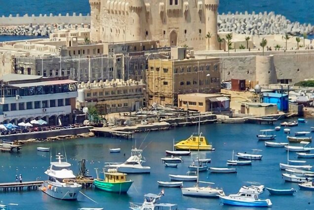 A scenic view of the Qaitbay Citadel with boats docked at the harbor in Alexandria, Egypt