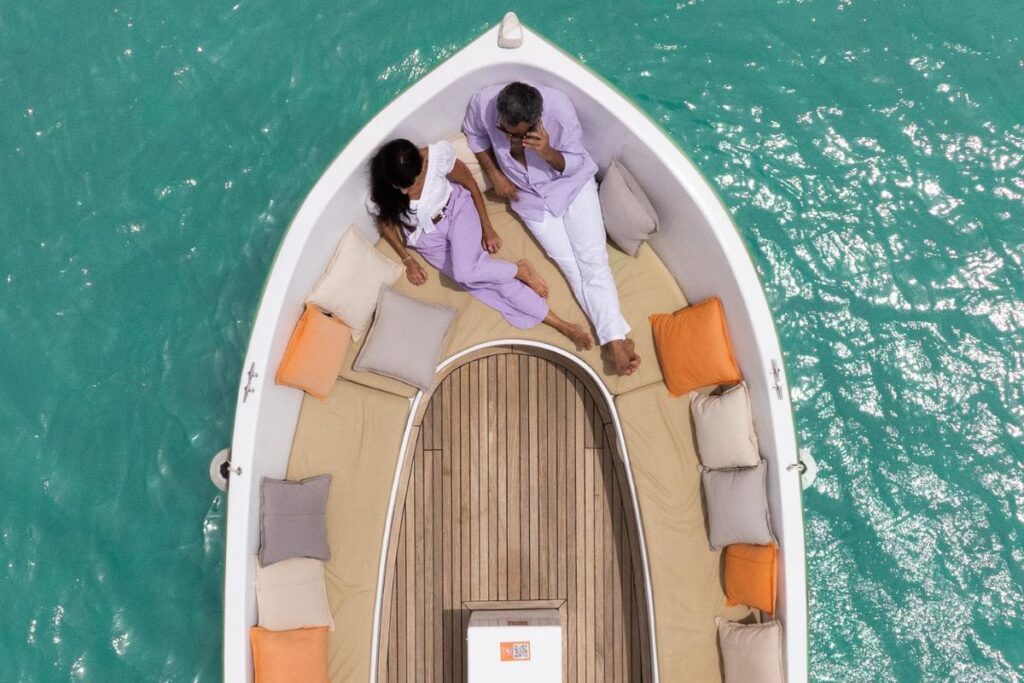 Couple relaxing on a boat with colorful cushions on a turquoise sea