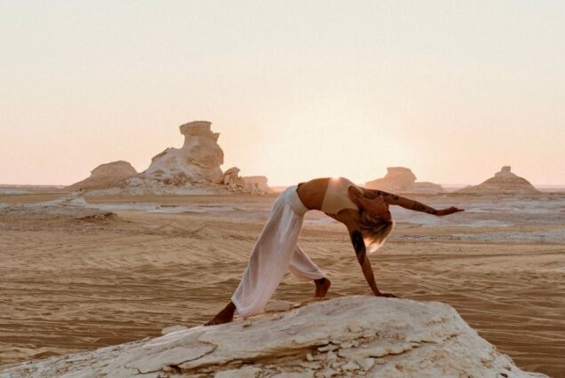 A person performing a yoga pose at sunrise in the White Desert of Egypt