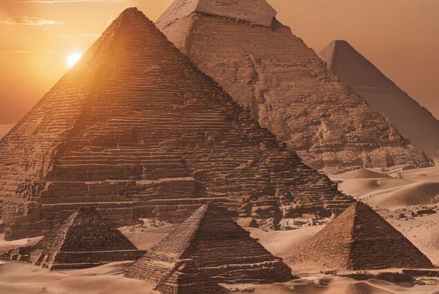 The Great Pyramids of Giza at sunset, casting long shadows in the desert