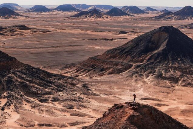 A view of Egypt’s Black Desert with towering dark hills against a vast sandy landscape