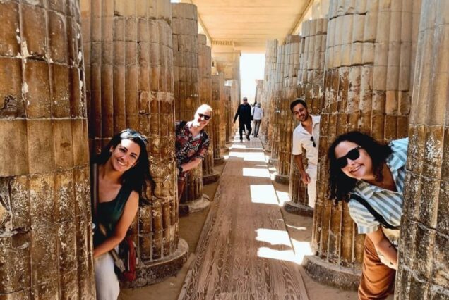 Group of tourists posing playfully behind ancient stone columns
