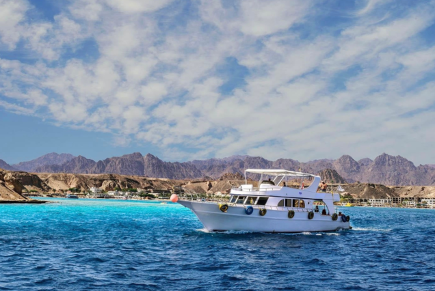 White yacht cruising the turquoise waters of the Red Sea with mountains in the background