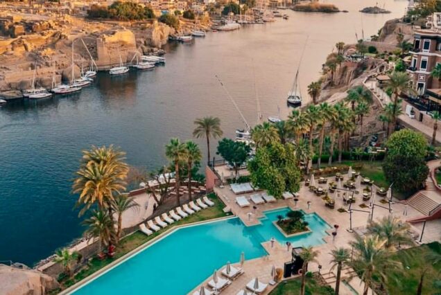 A panoramic view of the Nile River in Aswan with feluccas sailing and lush greenery along the banks, Egypt