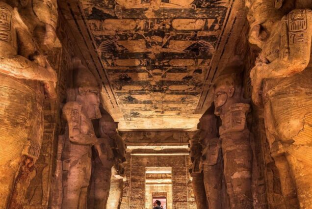 The grand entrance of Luxor Temple at dusk, with towering columns and statues illuminated against the evening sky