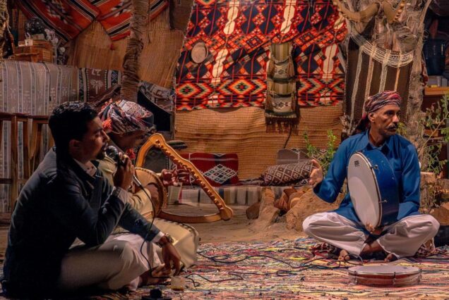 Traditional musicians playing instruments in a decorated Bedouin tent