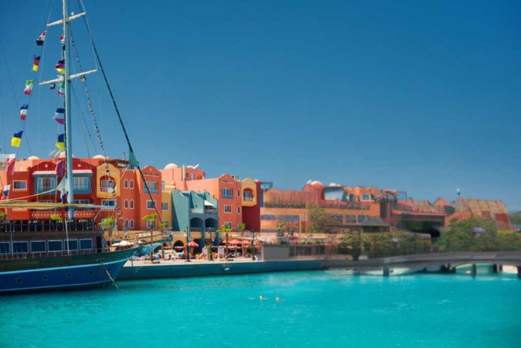 A vibrant marina with colorful buildings and a docked sailing boat on clear blue waters