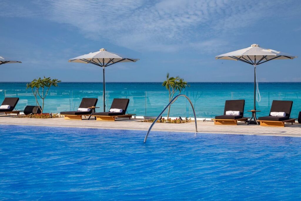 Wooden lounge chairs with soft cushions under a canopy of mint green fabric