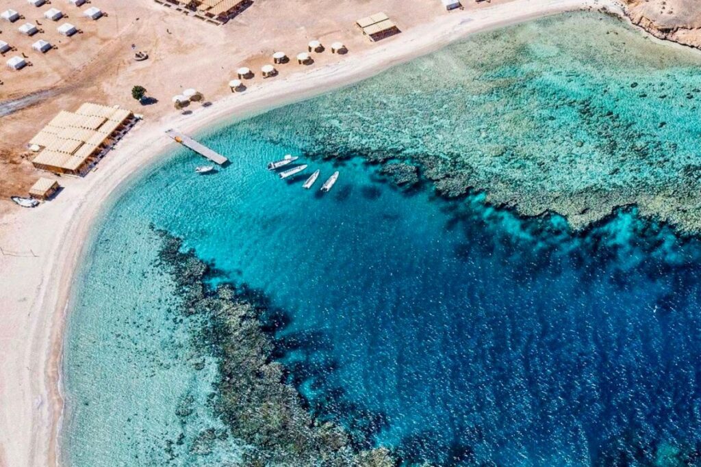 Aerial view of a secluded beach with a coral reef and crystal-clear waters